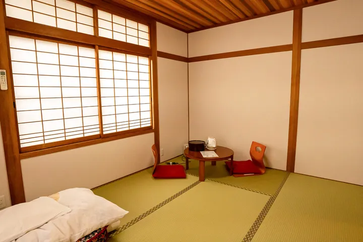 障子からやわらかい光が差す6畳の和室。座椅子と丸卓。